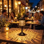 Two solar table lanterns with warm white light and decorative floral patterns on an outdoor patio table