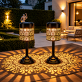 Two solar table lanterns with warm white light and decorative floral patterns on an outdoor patio table