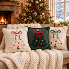 Embroidered Christmas pillow covers in cream and green with festive tree designs displayed on a cozy sofa.